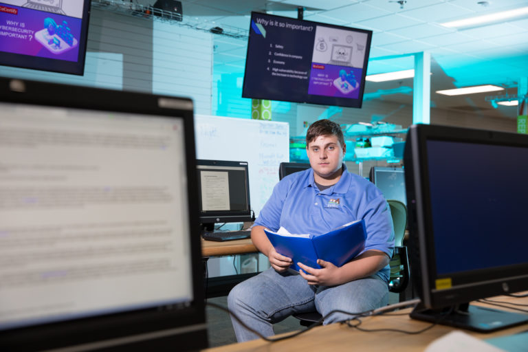 Eli Evans faces the camera, with computer monitors in the background