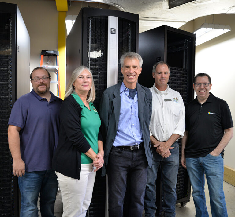 Representatives from Microsoft stand with SVHEC staff in front of a newly donated, decommissioned Microsoft server.