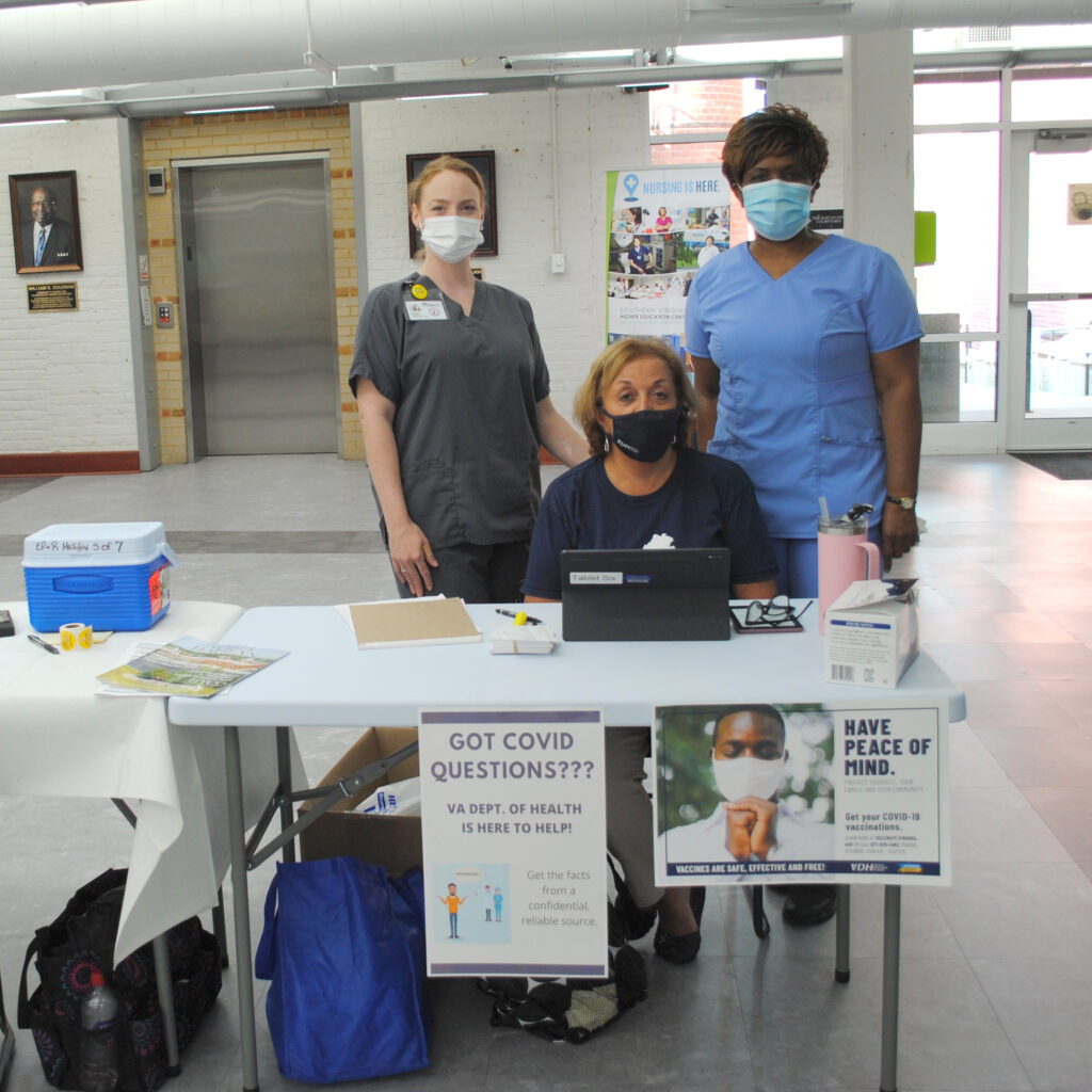 Image of three Virginia Department of Health workers. One individual is sitting and two individuals are standing immediately behind the seated individual. This 3-person team provided free COVID-19 vaccines at the Southern VA Higher Education Center on Sept.14, 2021.