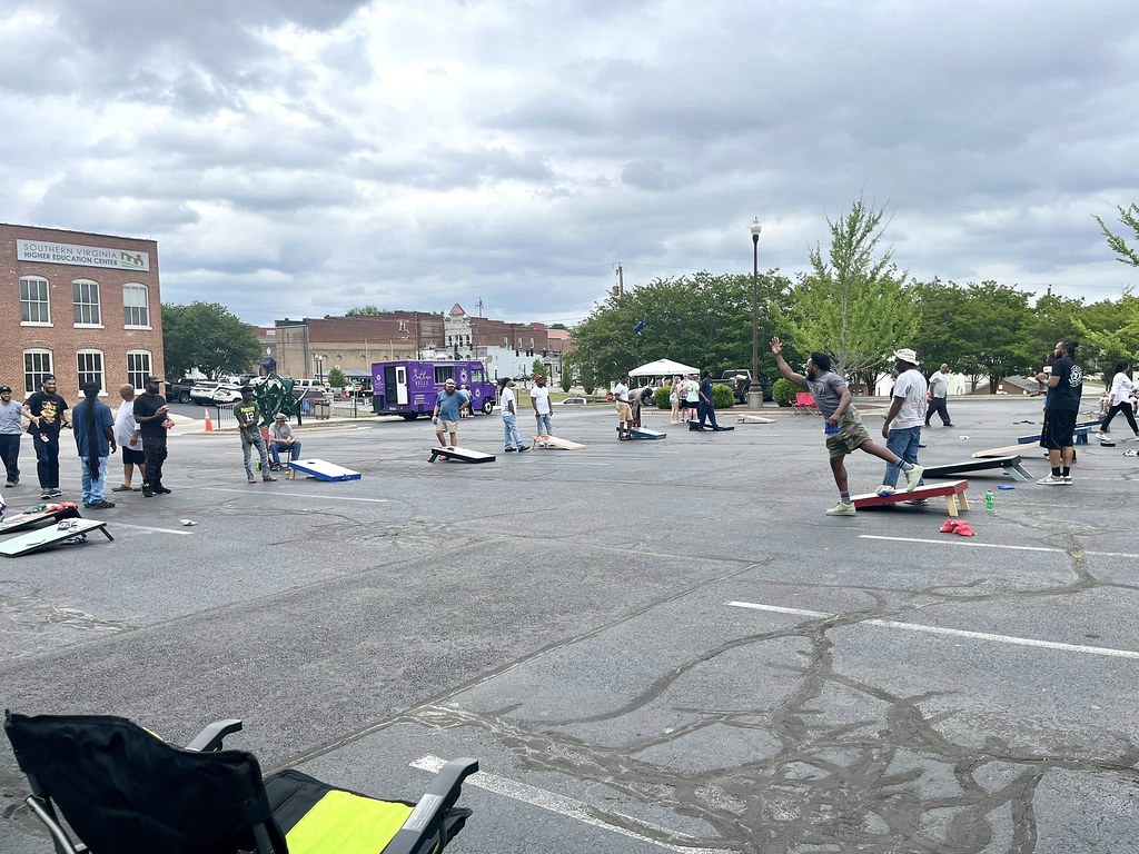 Photo of SVHEC parking lot with multiple corn hole boards set up. There is a man pictured in mid-throw and others are standing by their cornhole boards.